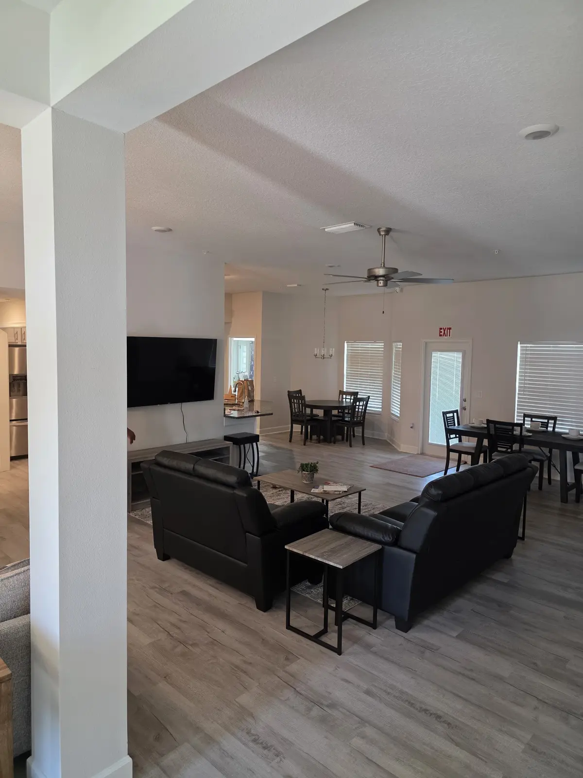 Furnished open living and dining space with comfortable seating, televisions and dining tables