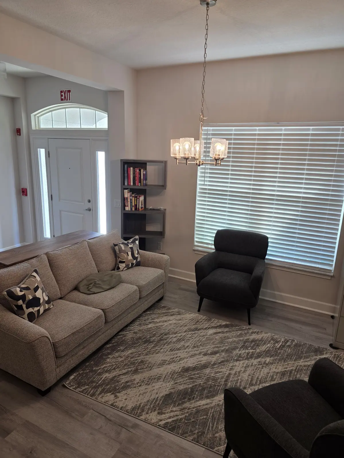 Cozy furnished sitting room with sofa, armchairs, area rug and books