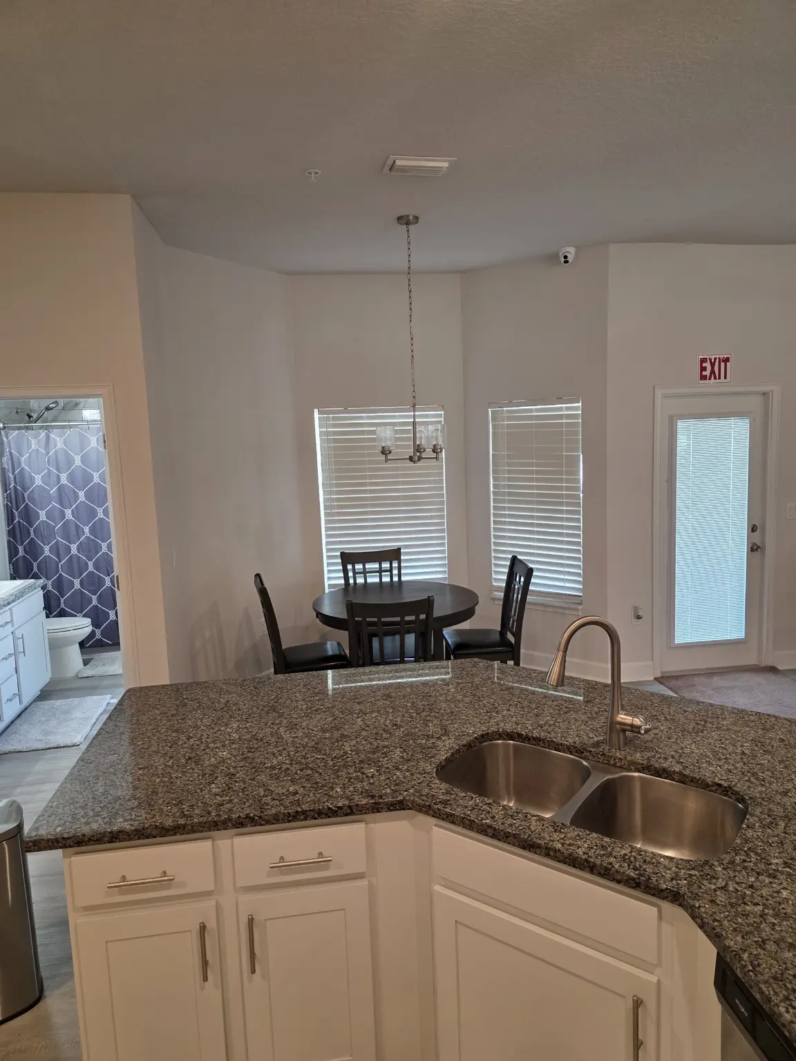 Granite kitchen island overlooking a breakfast table and nearby bathroom