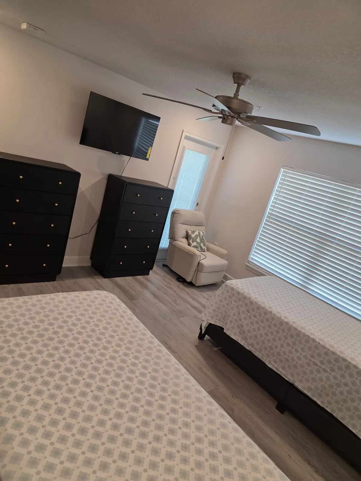 Furnished shared bedroom with two beds, dressers, television and recliner