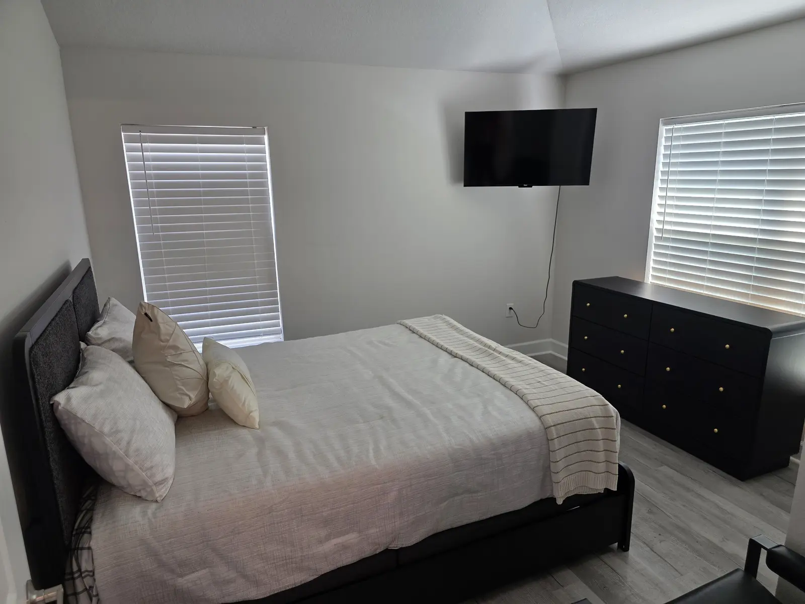 Furnished private bedroom with bed, dresser, television and natural light