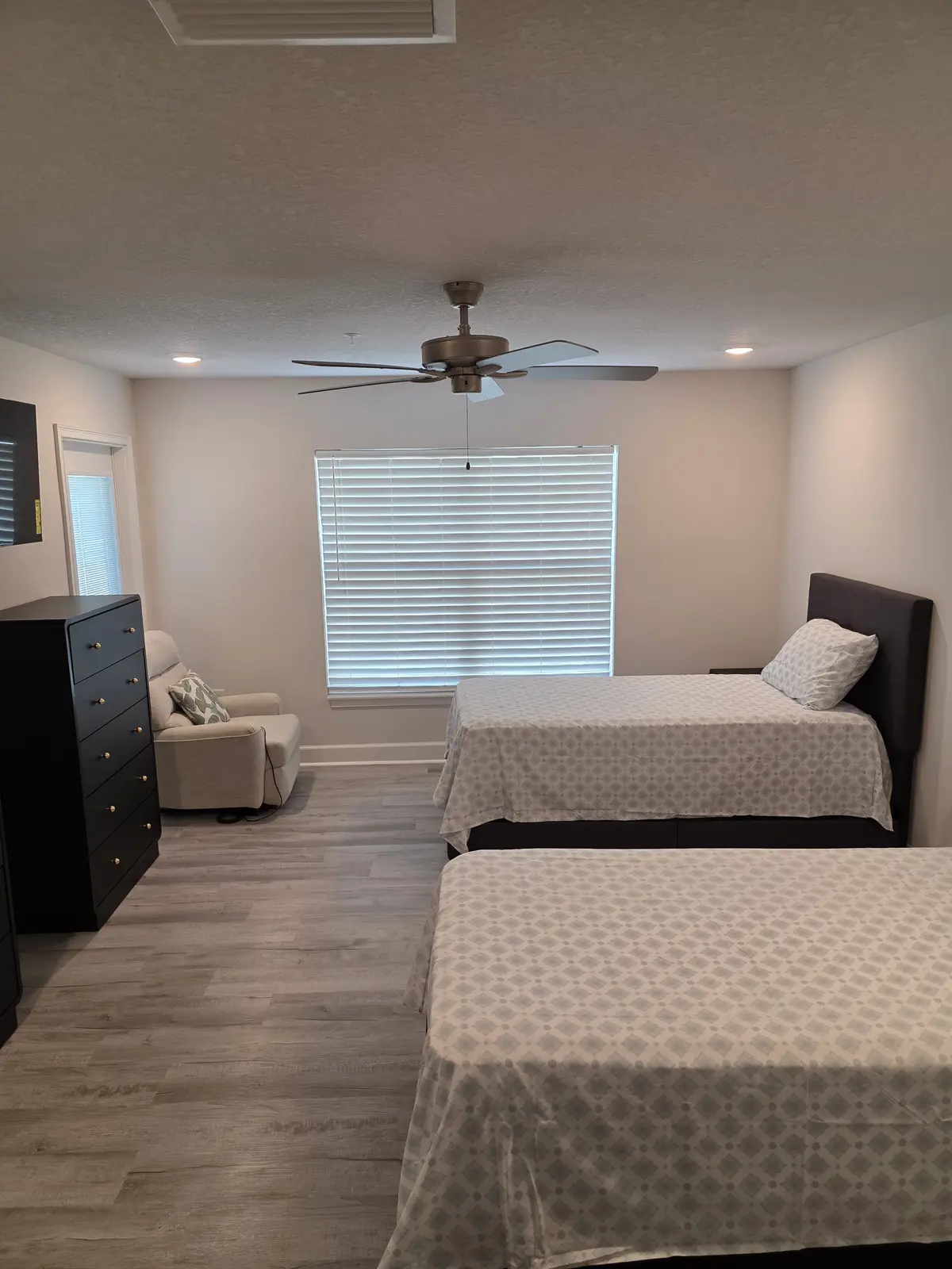 Spacious furnished shared bedroom with two beds, dresser, recliner and television
