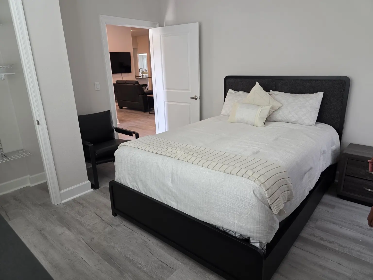 Furnished private bedroom with nearby closet and view toward the shared living area